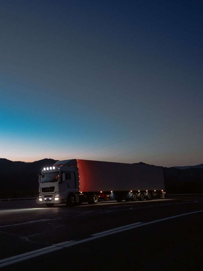 The Art of Drawing Readers In: Your attractive post title goes here A large truck travels on a highway at dusk surrounded by mountains, showcasing travel and logistics.
