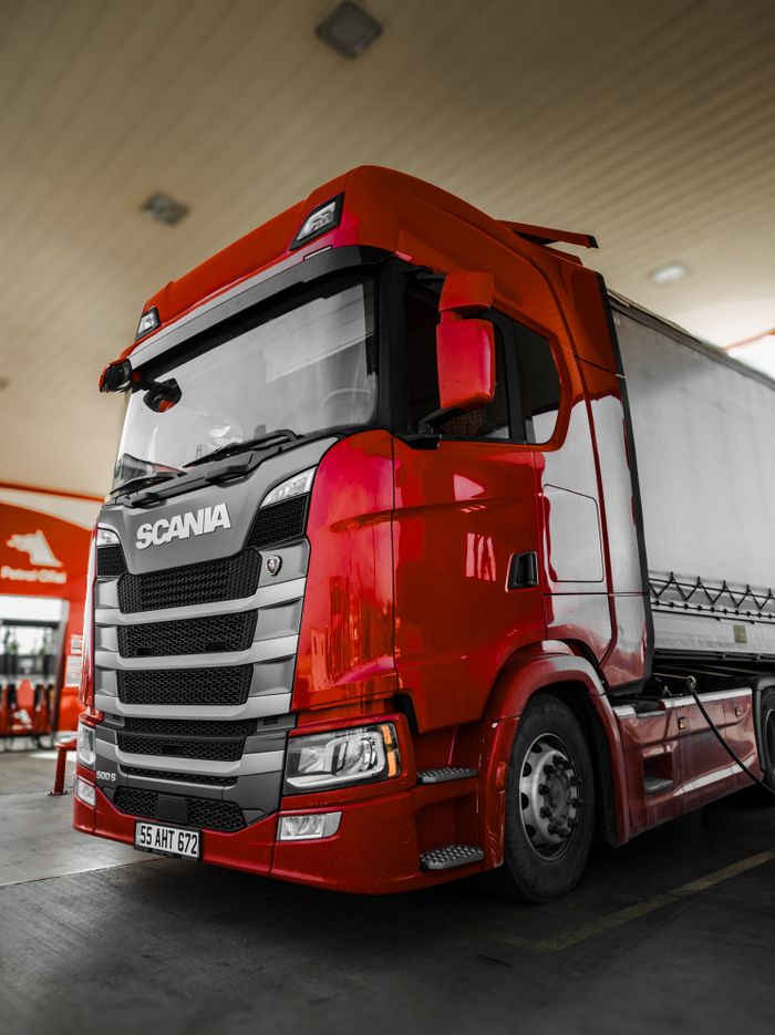 Crafting Captivating Headlines: Your awesome post title goes here Bright red Scania truck parked at a fuel station with modern design and clean lines.